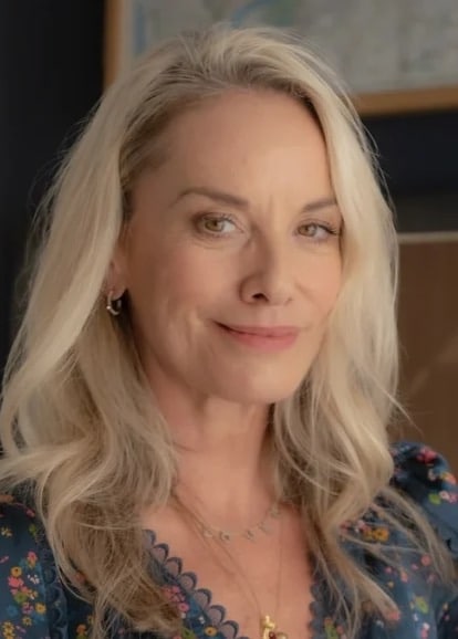 Portrait of a smiling woman with long wavy blonde hair and a floral patterned top