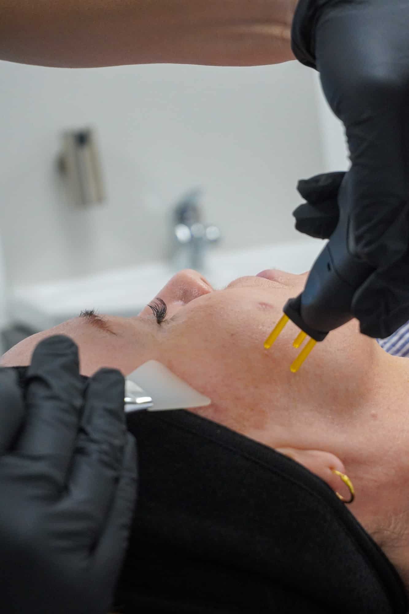 Practitioner treating a reclining patient’s cheek with the gold-tipped NeoGen handpiece