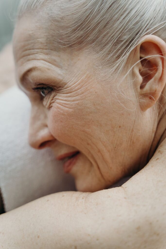 Close-up of an older woman with silver hair, smiling softly in profile